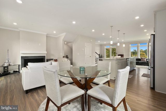 dining room featuring ornamental molding, sink, and dark hardwood / wood-style floors