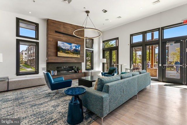 living room featuring a fireplace, light wood-type flooring, and a towering ceiling