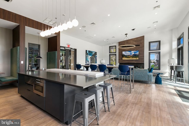 kitchen featuring light hardwood / wood-style floors, wood walls, decorative light fixtures, and a kitchen breakfast bar