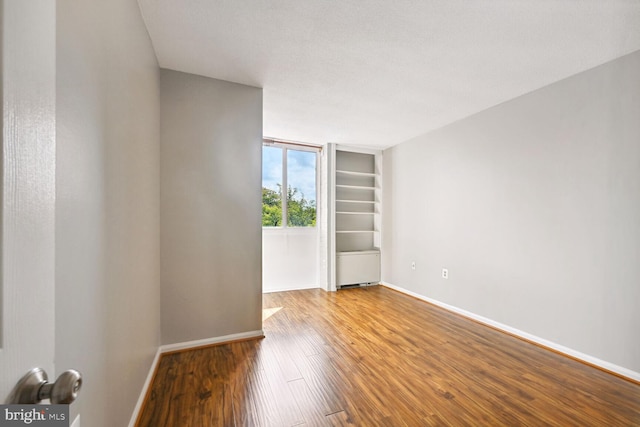 empty room with hardwood / wood-style floors and a textured ceiling