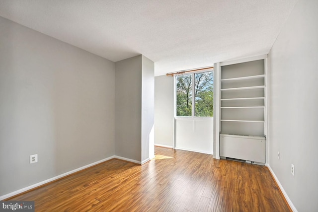 unfurnished room with a textured ceiling and wood-type flooring