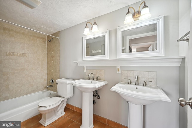 bathroom featuring toilet, tile patterned floors, tiled shower / bath combo, and a textured ceiling