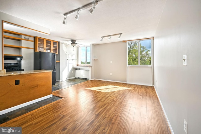 unfurnished living room with rail lighting, a textured ceiling, dark hardwood / wood-style floors, and ceiling fan