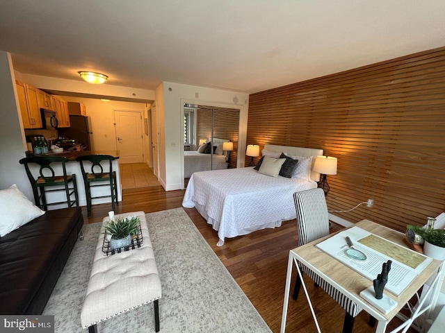 bedroom featuring black refrigerator and dark hardwood / wood-style flooring