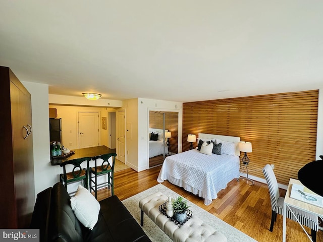 bedroom with black refrigerator and light hardwood / wood-style floors