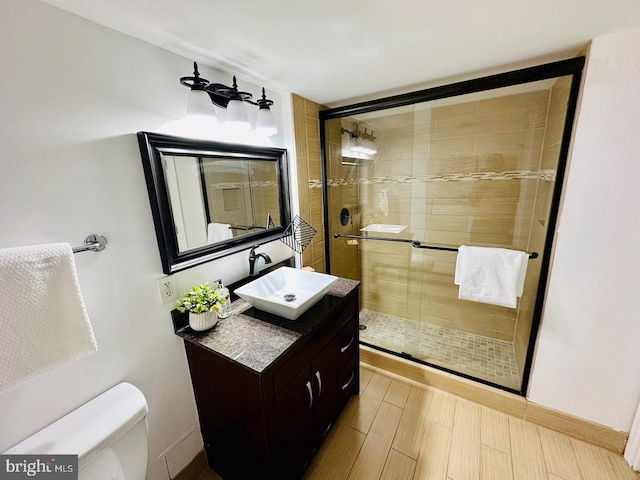 bathroom featuring a shower with door, vanity, and toilet