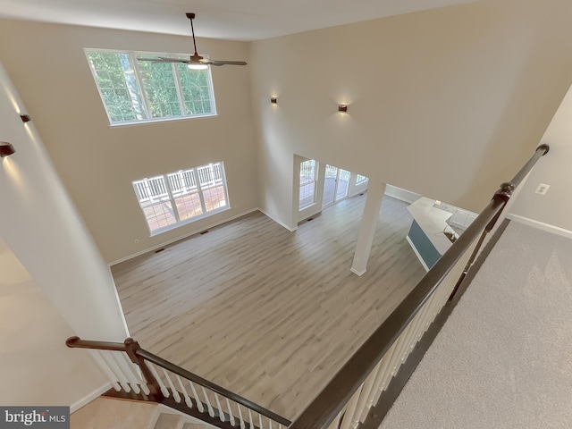 staircase with hardwood / wood-style floors and ceiling fan