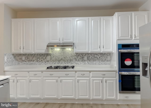 kitchen with tasteful backsplash, appliances with stainless steel finishes, light hardwood / wood-style flooring, and white cabinets