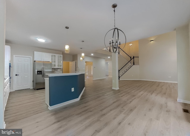 kitchen with a kitchen island, light hardwood / wood-style flooring, stainless steel fridge, decorative light fixtures, and white cabinetry