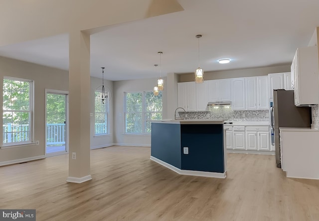 kitchen featuring an island with sink, white cabinets, a healthy amount of sunlight, and pendant lighting