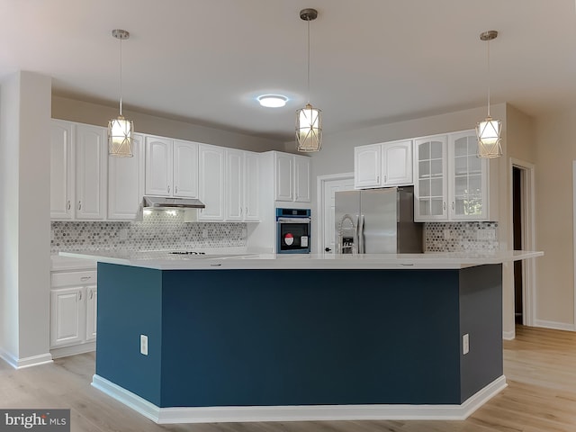 kitchen featuring appliances with stainless steel finishes, white cabinets, a center island with sink, and backsplash