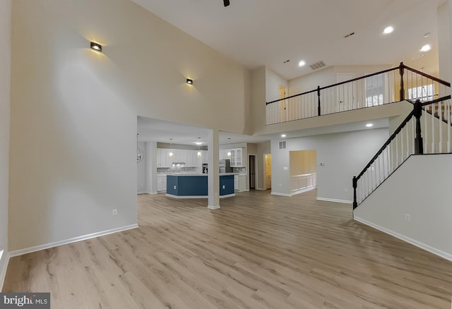 unfurnished living room with light hardwood / wood-style floors and high vaulted ceiling