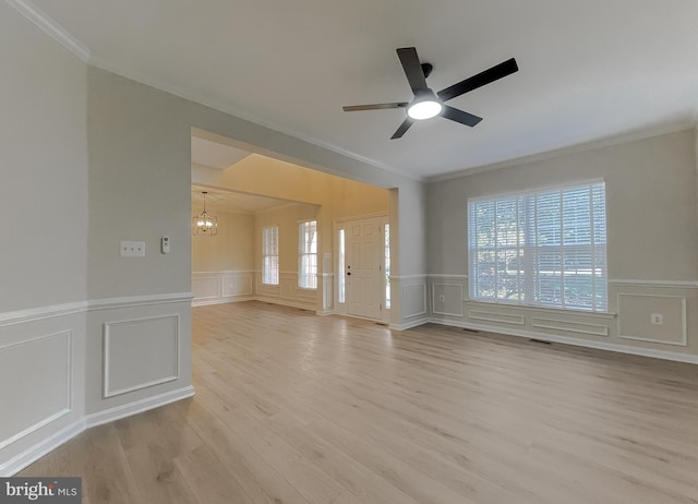 unfurnished room featuring crown molding, light wood-type flooring, and ceiling fan with notable chandelier