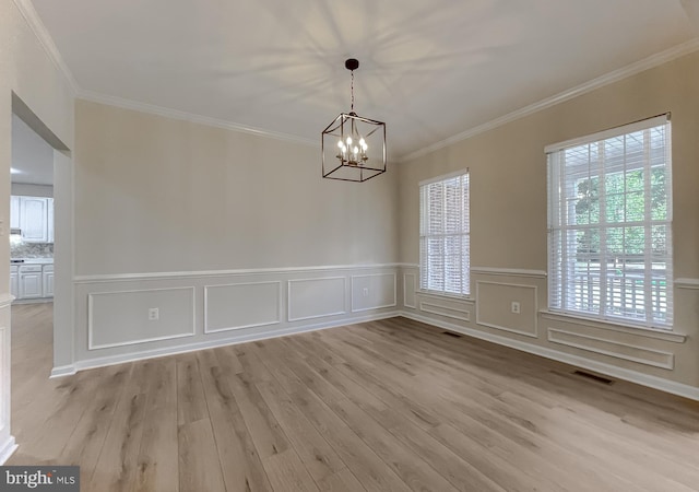 empty room with light hardwood / wood-style floors, crown molding, and a notable chandelier