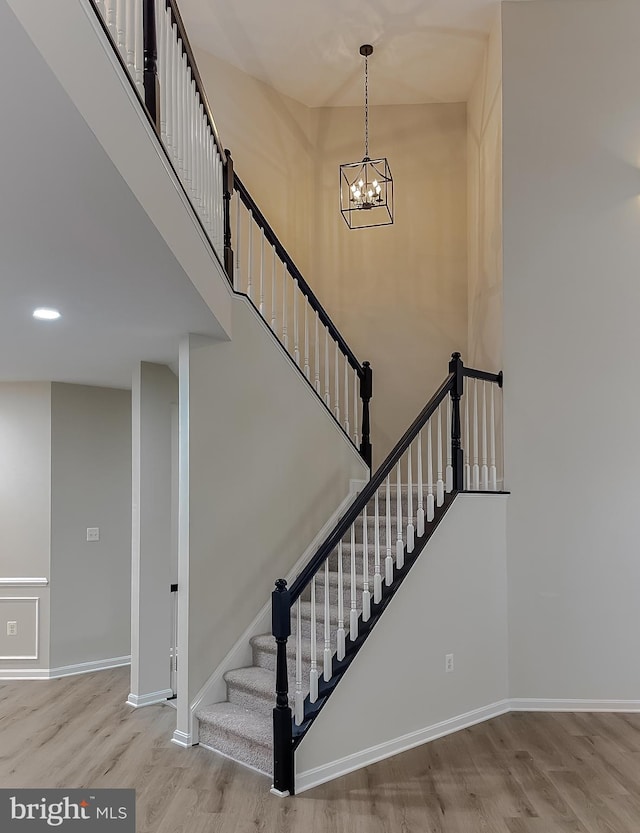 stairs featuring a notable chandelier and wood-type flooring