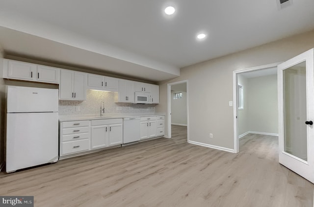 kitchen with backsplash, white cabinetry, light hardwood / wood-style flooring, and white appliances