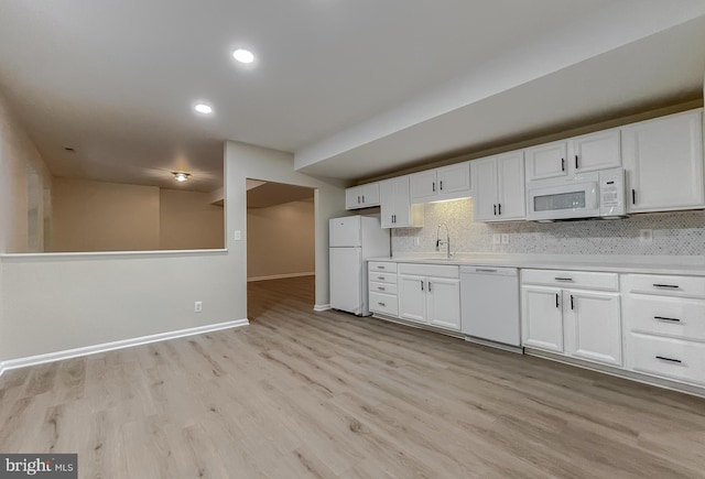 kitchen with white appliances, light hardwood / wood-style floors, white cabinetry, and decorative backsplash