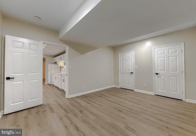 basement with light hardwood / wood-style floors and white refrigerator