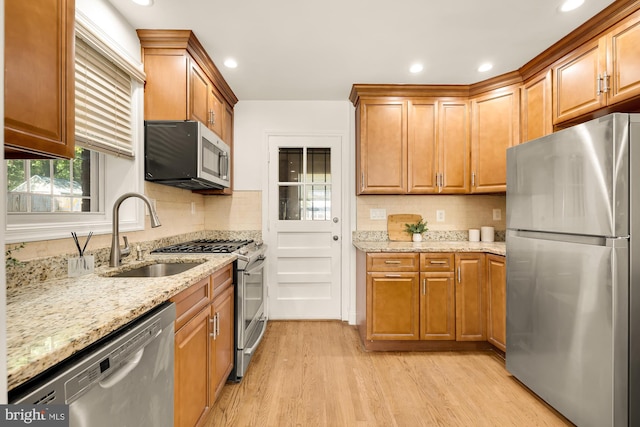 kitchen featuring sink, light stone countertops, stainless steel appliances, and light hardwood / wood-style floors