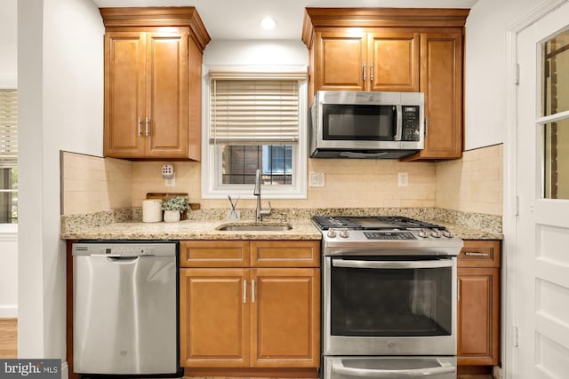 kitchen featuring backsplash, stainless steel appliances, sink, and light stone counters