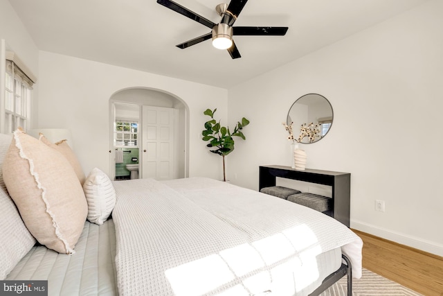 bedroom featuring light hardwood / wood-style floors, ensuite bathroom, and ceiling fan