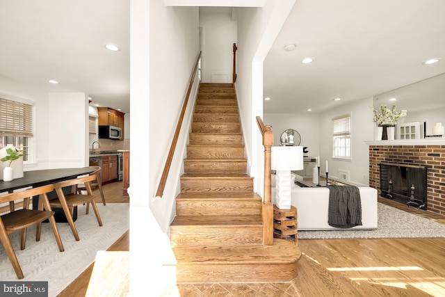 staircase with a fireplace and hardwood / wood-style floors