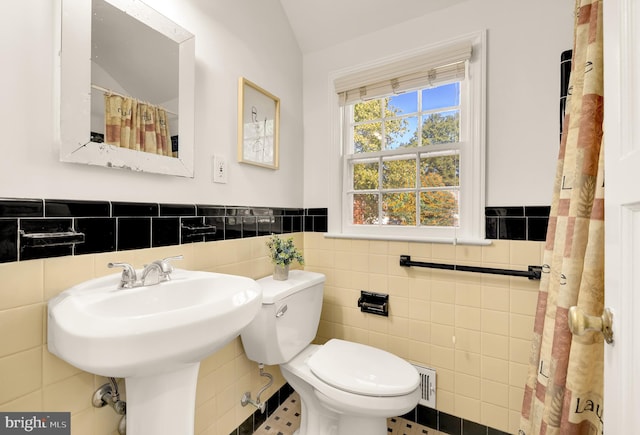 bathroom featuring toilet, tile patterned floors, and tile walls