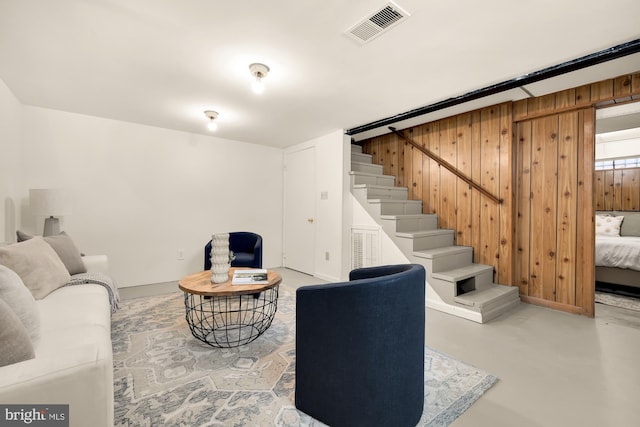 living room featuring wooden walls and concrete floors