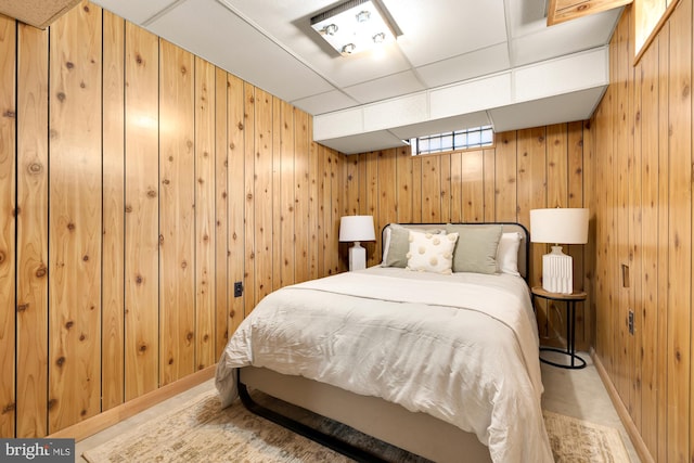 bedroom with a paneled ceiling and wood walls