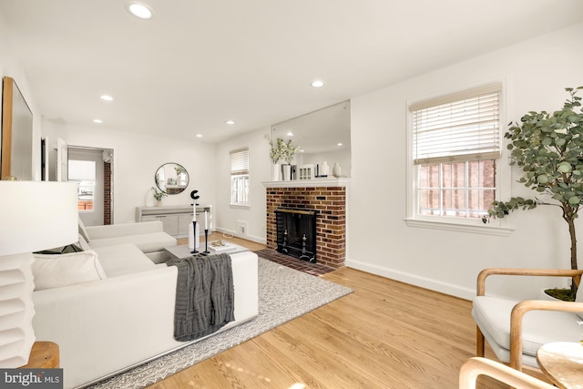 living room featuring light hardwood / wood-style flooring and a brick fireplace