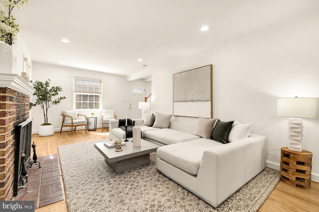 living room with a brick fireplace and hardwood / wood-style flooring