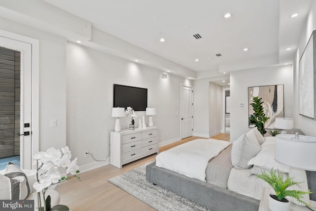 bedroom with light hardwood / wood-style floors and ensuite bathroom