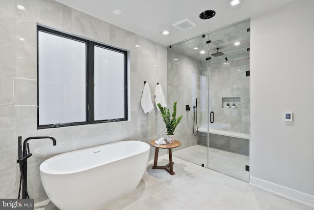 bathroom with tile walls and independent shower and bath