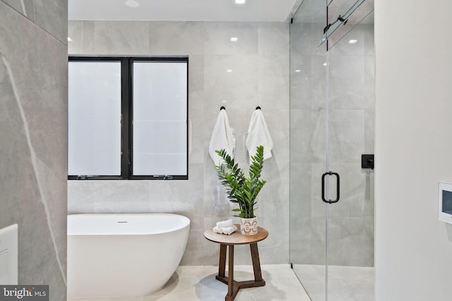 bathroom featuring independent shower and bath and tile walls