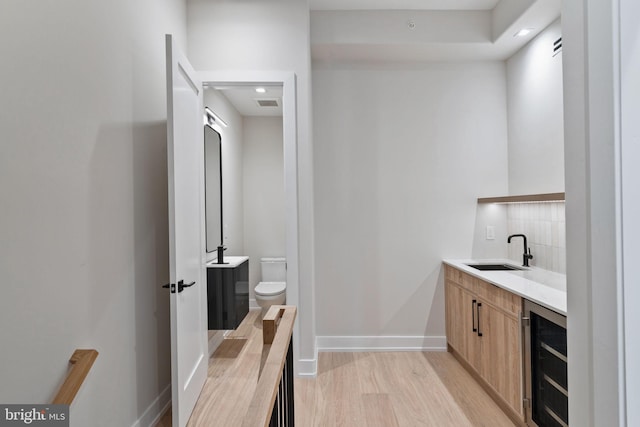 bathroom featuring hardwood / wood-style floors, vanity, beverage cooler, toilet, and backsplash