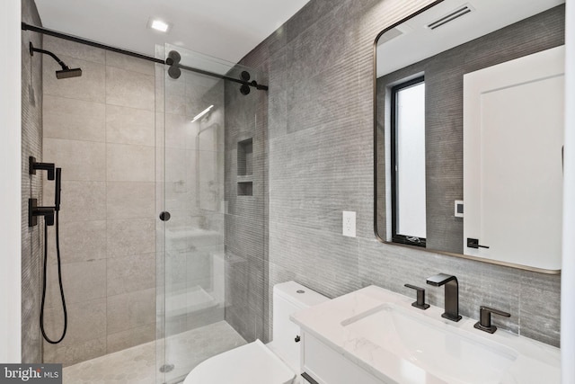 bathroom with toilet, tile walls, backsplash, a shower with door, and vanity