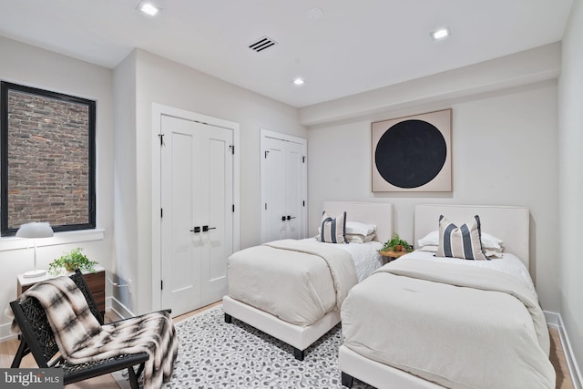 bedroom featuring light wood-type flooring and two closets