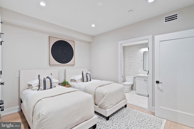 bedroom featuring connected bathroom and light wood-type flooring