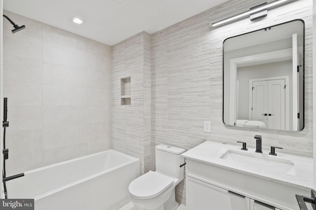 full bathroom with toilet, tile walls, vanity, and tiled shower / bath combo