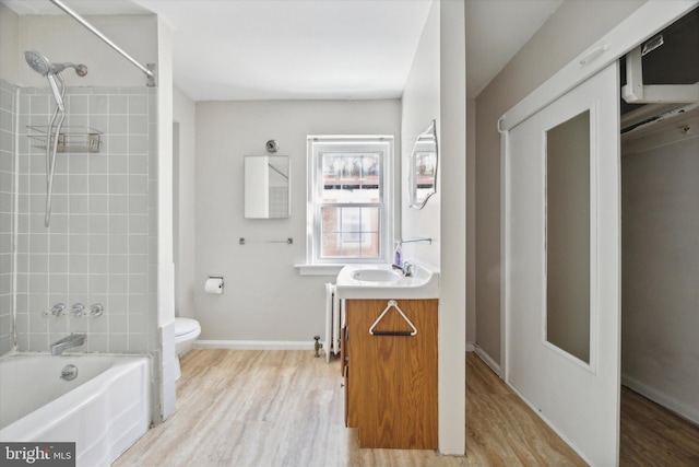 full bathroom with vanity, hardwood / wood-style floors, tiled shower / bath combo, and toilet