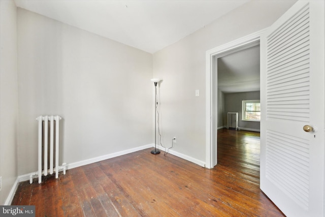 spare room with dark wood-type flooring and radiator heating unit