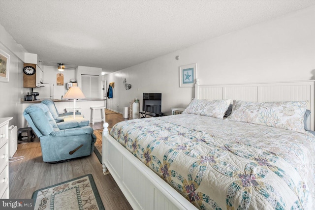 bedroom with a textured ceiling and dark hardwood / wood-style floors