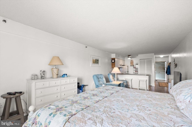 bedroom with hardwood / wood-style floors, white fridge, and a textured ceiling