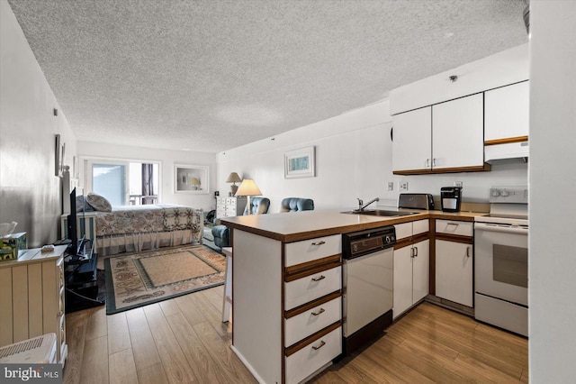 kitchen featuring white appliances, sink, kitchen peninsula, light hardwood / wood-style floors, and white cabinets