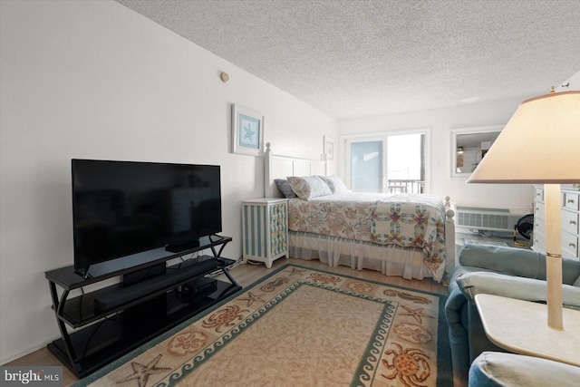 bedroom with hardwood / wood-style flooring, a textured ceiling, and a wall unit AC