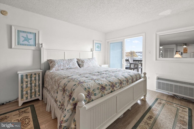 bedroom with a textured ceiling, wood-type flooring, and access to outside