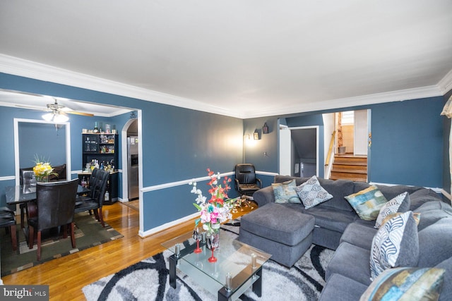 living room featuring wood-type flooring, crown molding, and ceiling fan