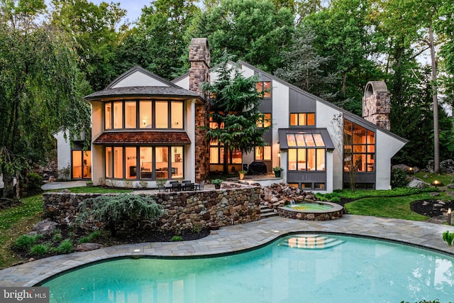 rear view of property with a patio and a swimming pool with hot tub