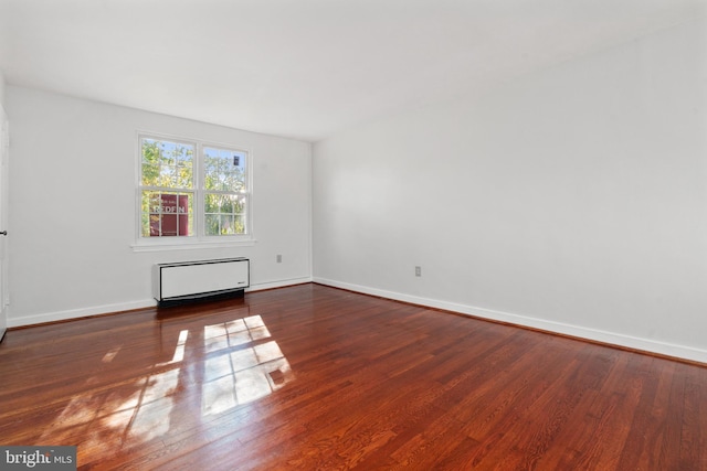 empty room with dark hardwood / wood-style floors and radiator