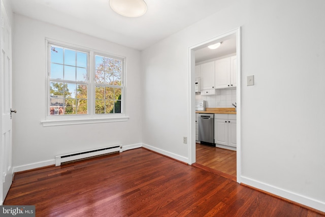 unfurnished room with a baseboard heating unit, sink, and dark hardwood / wood-style flooring